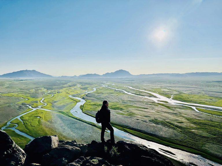 Pujee - a trip assistant with Eternal Landscapes - achieving new heights standing on top of a mountain overlooking a river